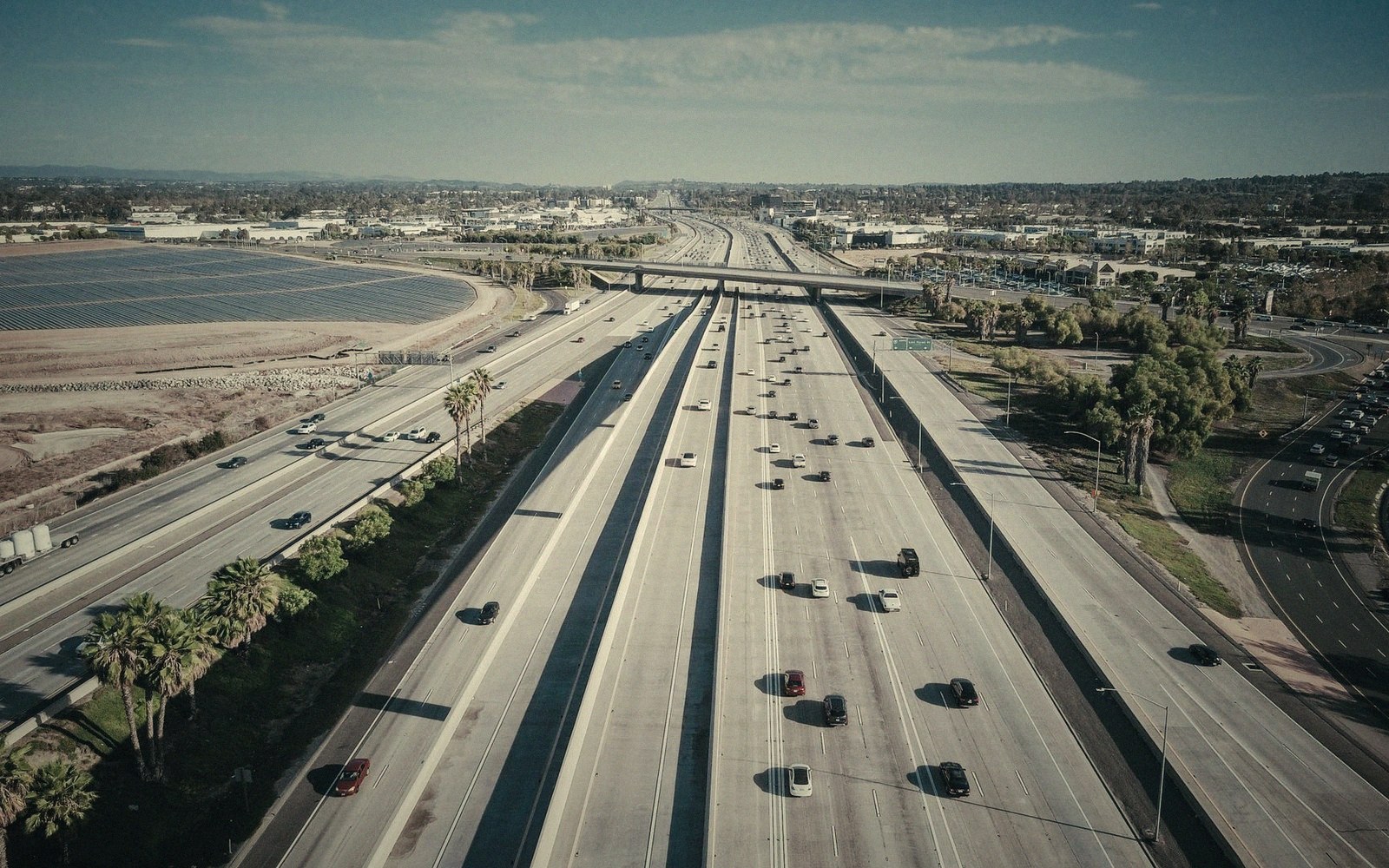 Aerial view of a multi-lane freeway with light traffic cutting through suburban sprawl