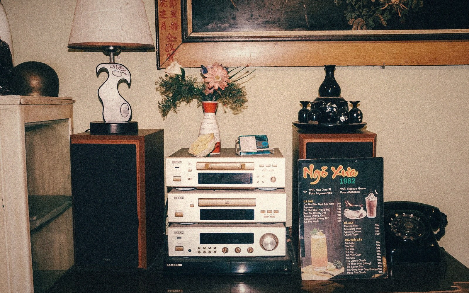 Vintage stereo components, flowers and a rotary phone sit beside a café menu stand